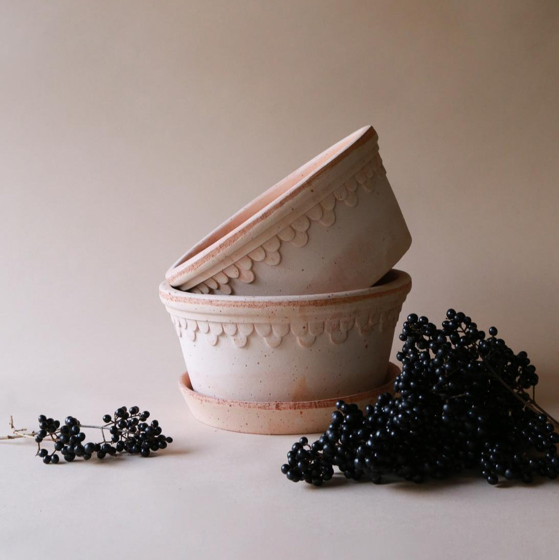 Two terracotta pots with decorative patterns on a plain background