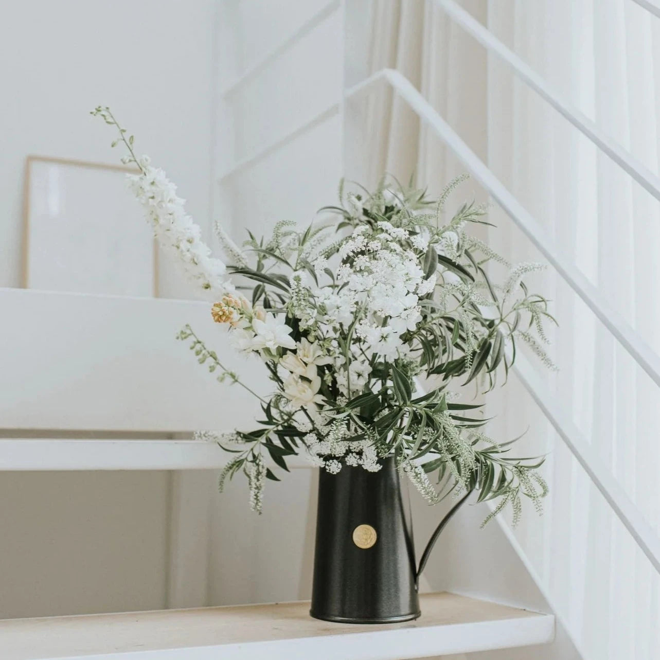 Haws Classic Jug in Graphite shown with a white flower arrangement