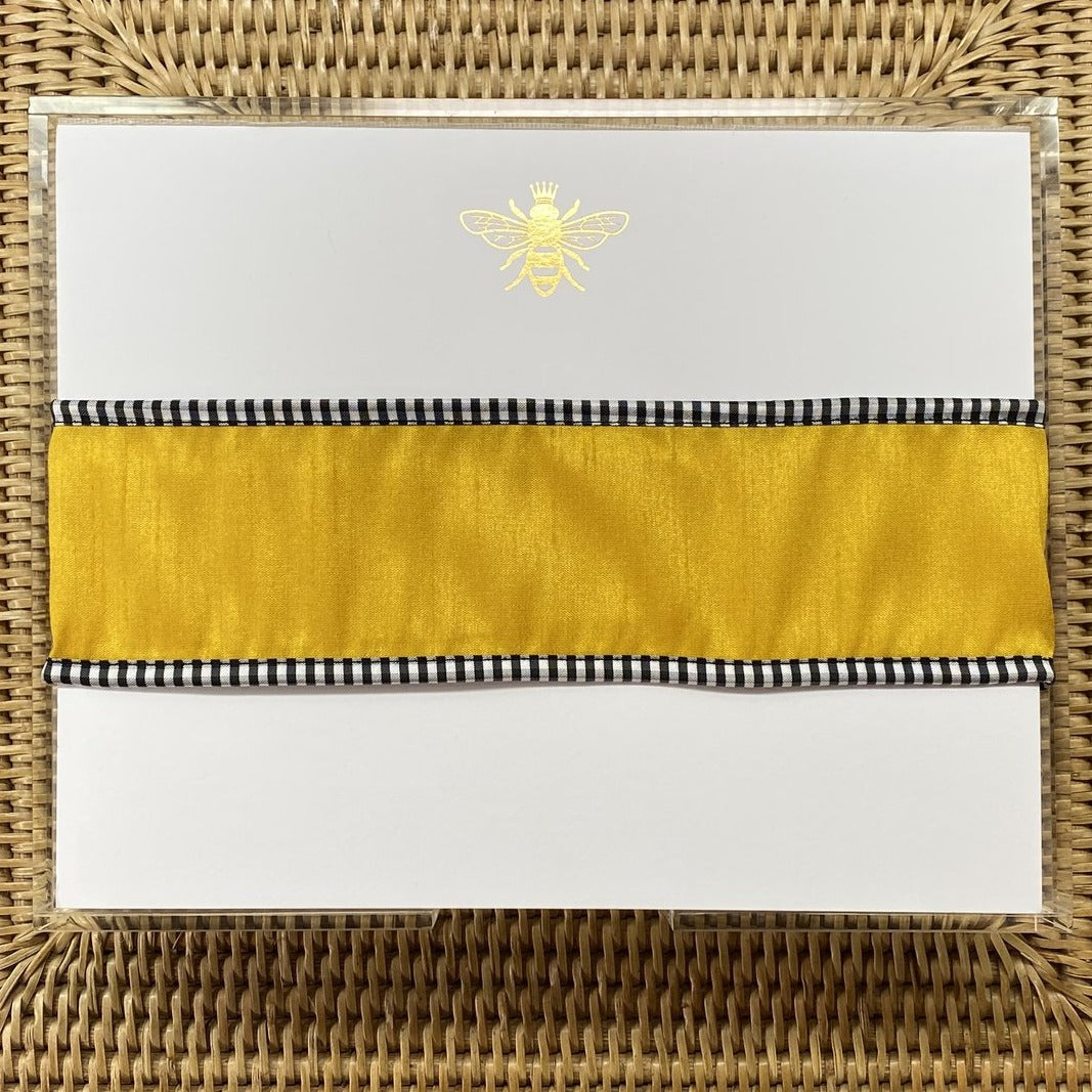 The Gold embossed note pad shown with a gold ribbon around it.
