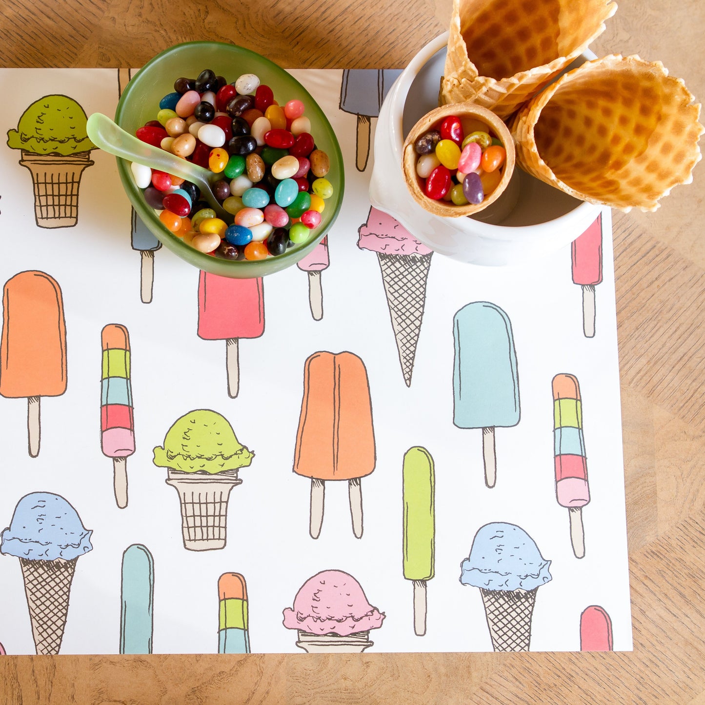 Ice cream social paper placemat is shown here with a bowl of jelly beans and crisp waffle ice cream cones for a fun childrens party.