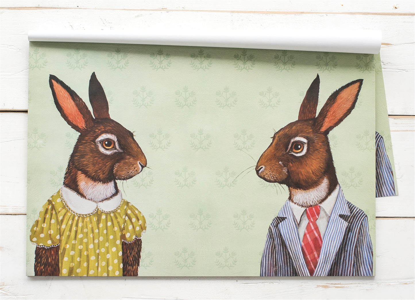 A placemat with a female and a male rabbit facing each other dressed for a meal. This placemat has be a best seller.