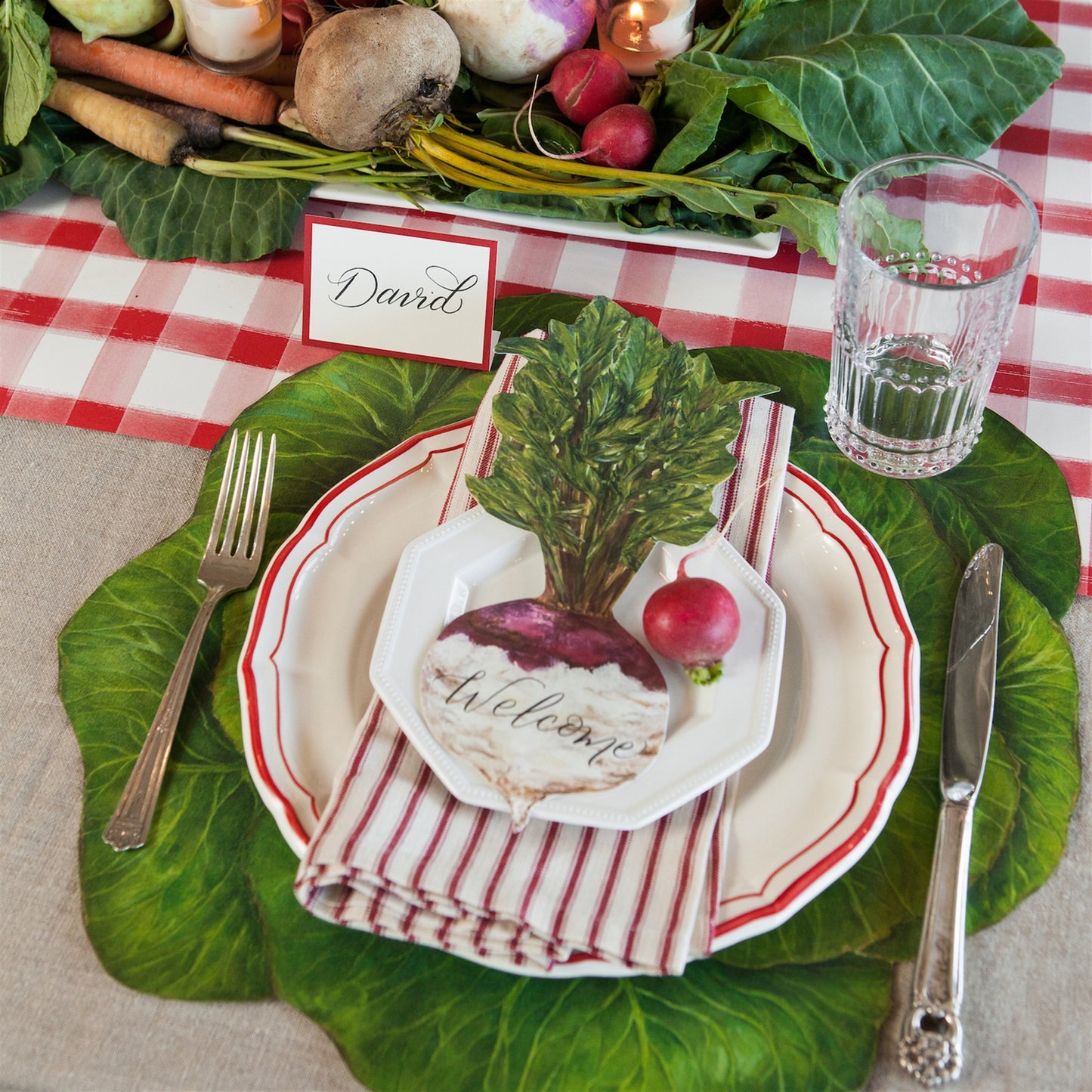 A picture of the green cabbage placemat being used at a table setting. It has white dishes trimmed with red and a turnip place card.