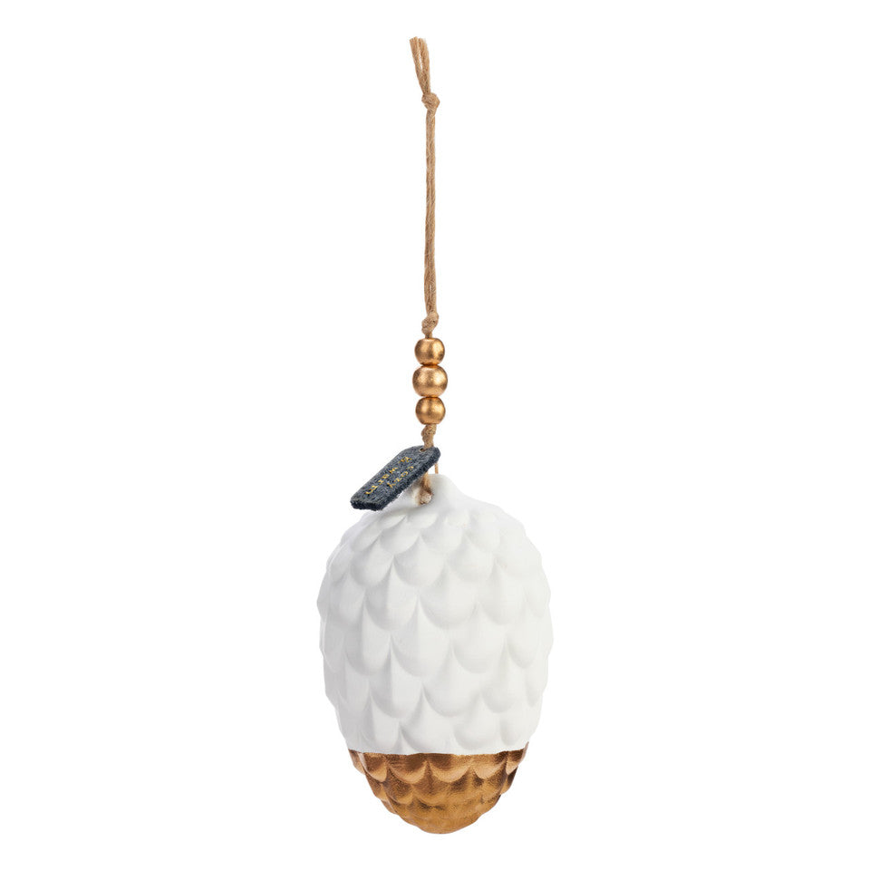This is a picture of the Pine Cone Diffuser Ornament. It is a white ceramic pine cone dipped in gold at the tip, and is hung by a string with gold beads and a small sign saying "cozy and warm."