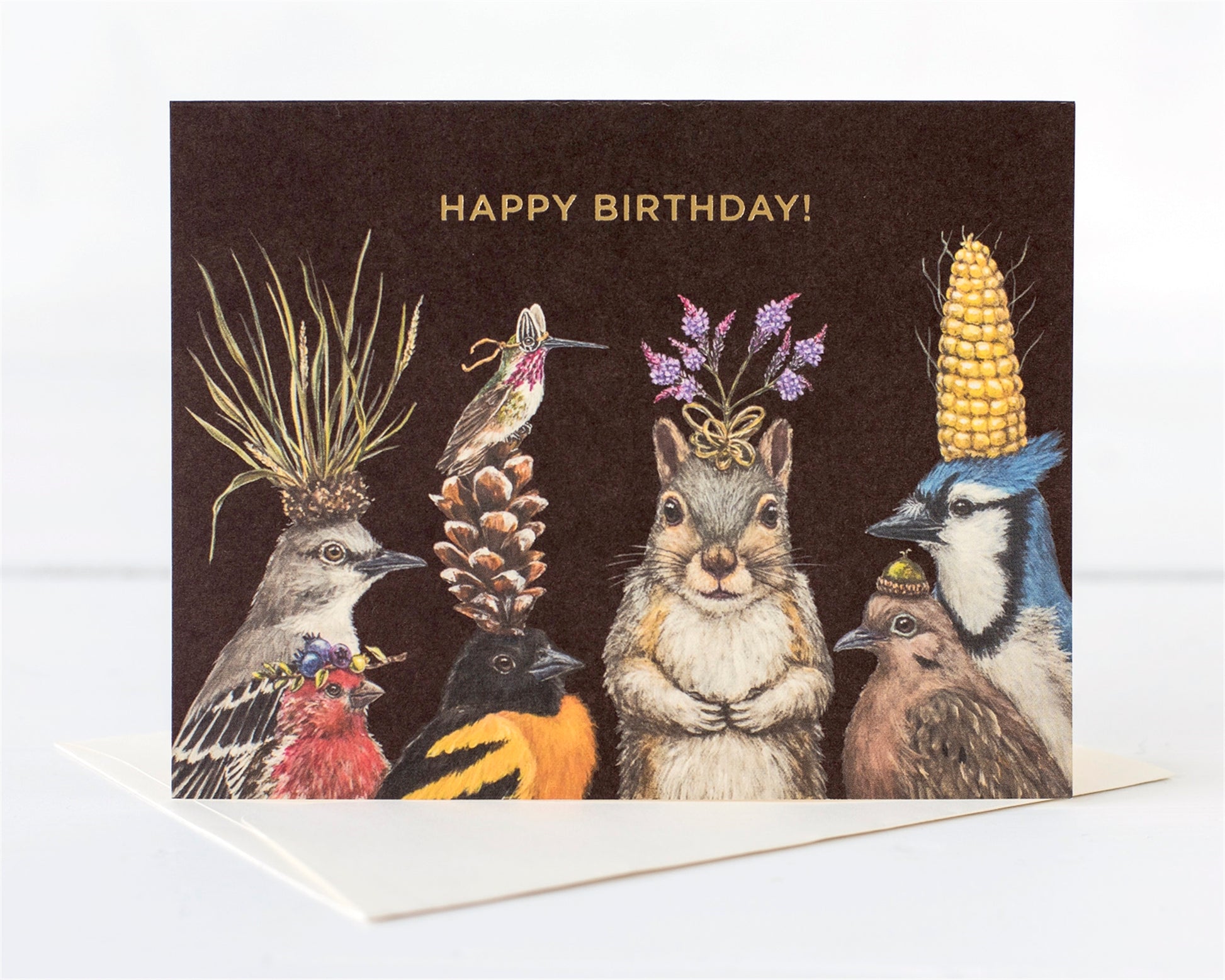 A group of woodland creatures' heads adorned with nature's bounty of flowers, nuts, pinecones, dressed up to wish you Happy Birthday