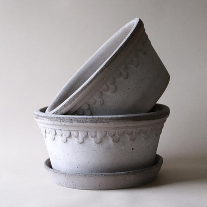 Two gray ceramic pots with decorative patterns on a light background