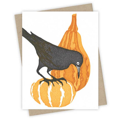 A grackle is perched on decorative gourds, celebrating the autumn season. 