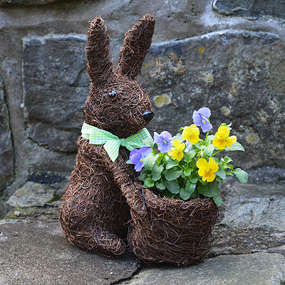 Rabbit topiary planter with yellow and purple flowers in it's basket