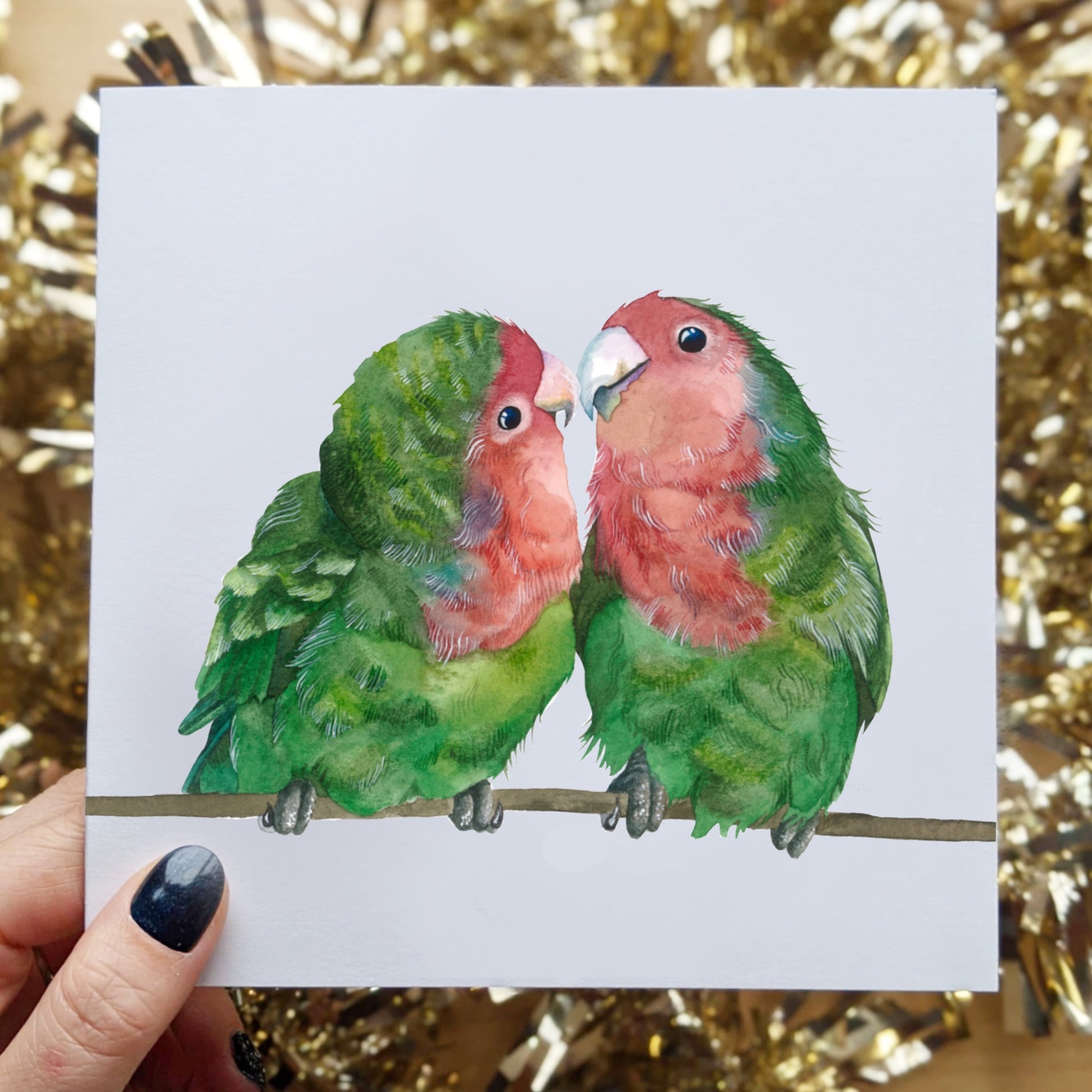 The cutest watercoloring of Love Birds. So sweet, their bright green and pink coloring is so pretty. They are setting on branch kissing.