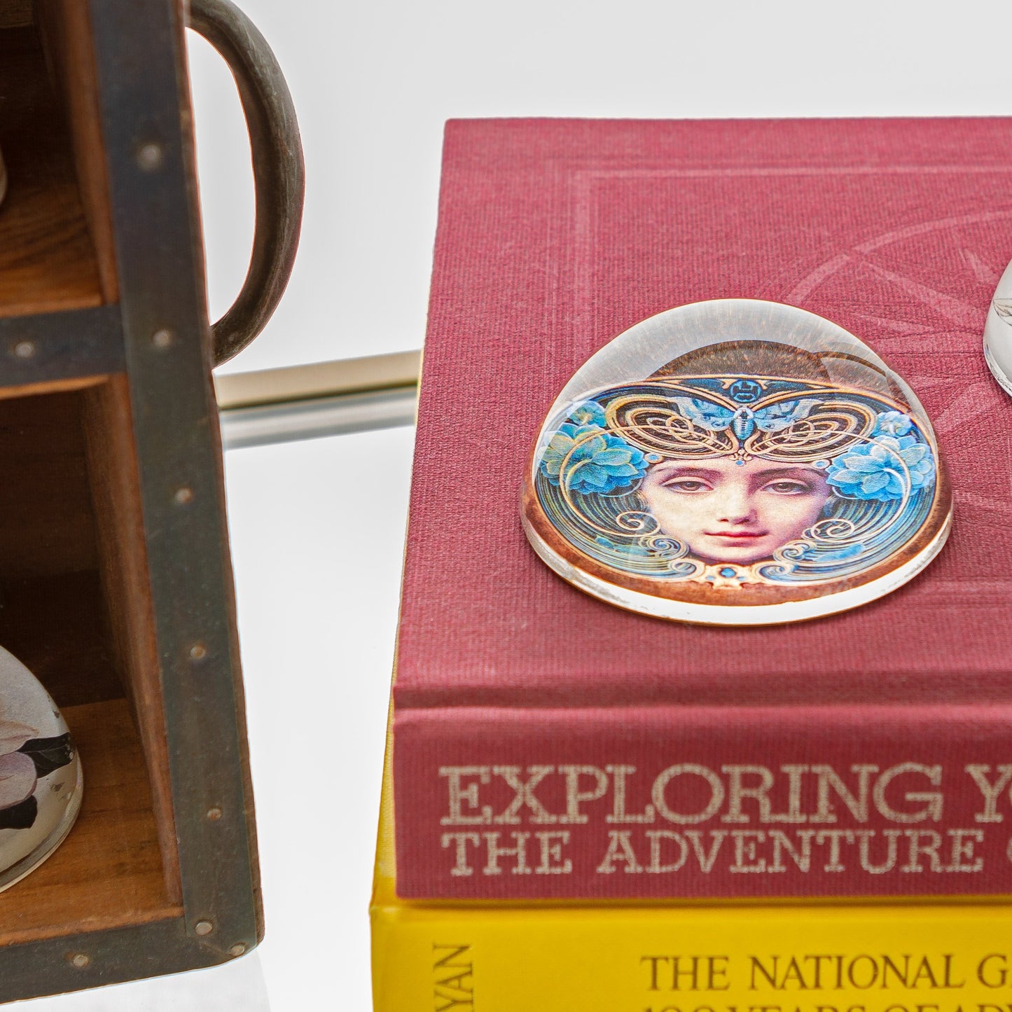 Crystal Domed Paperweight decoupaged with a Art Nouveau Woman's face shown  sitting on a stack of books