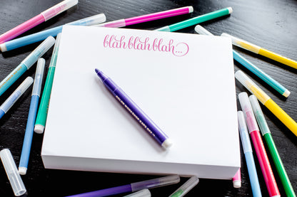 A photo of the Blah blah blah note pad shown with colorful felt pens scattered about.