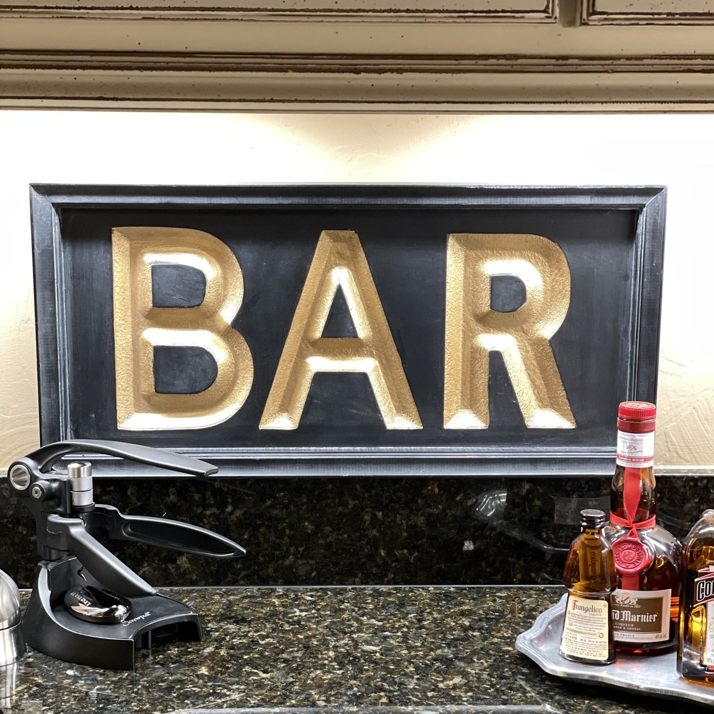 A black and gold bar sign setting in a butlers pantry.
