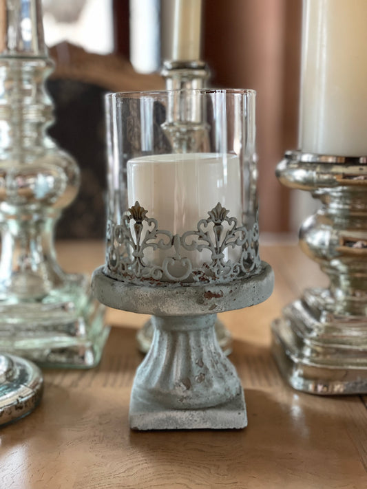 I have placed the cement hurricane candle holder in with my mercury candle holders and it looks right at home. It has a filigree boarder around the base and it is finished in a aged blueish gray. Quite unusual and will make a lovely statement on your patio.l 
