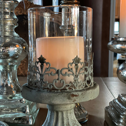 The cement hurricane candle emits a soft glow through it's glass chimney.