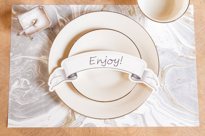 Showing a place setting with the black banner with the word enjoy written across it.