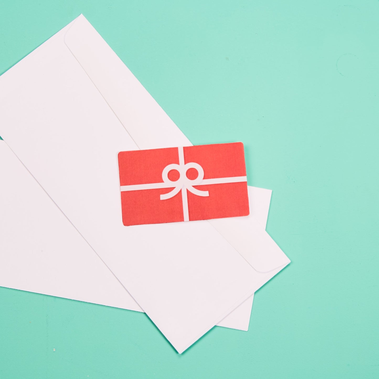 A picture of a bright red gift card laying on white envelops.