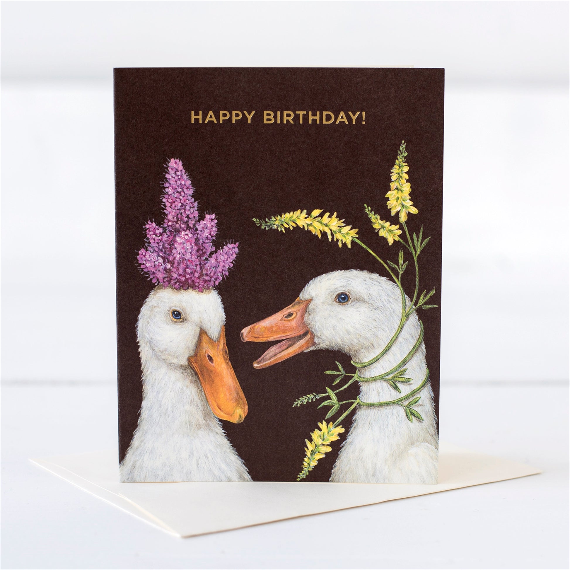 Two white ducks with flowers on their head as hats wishing a happy birthday