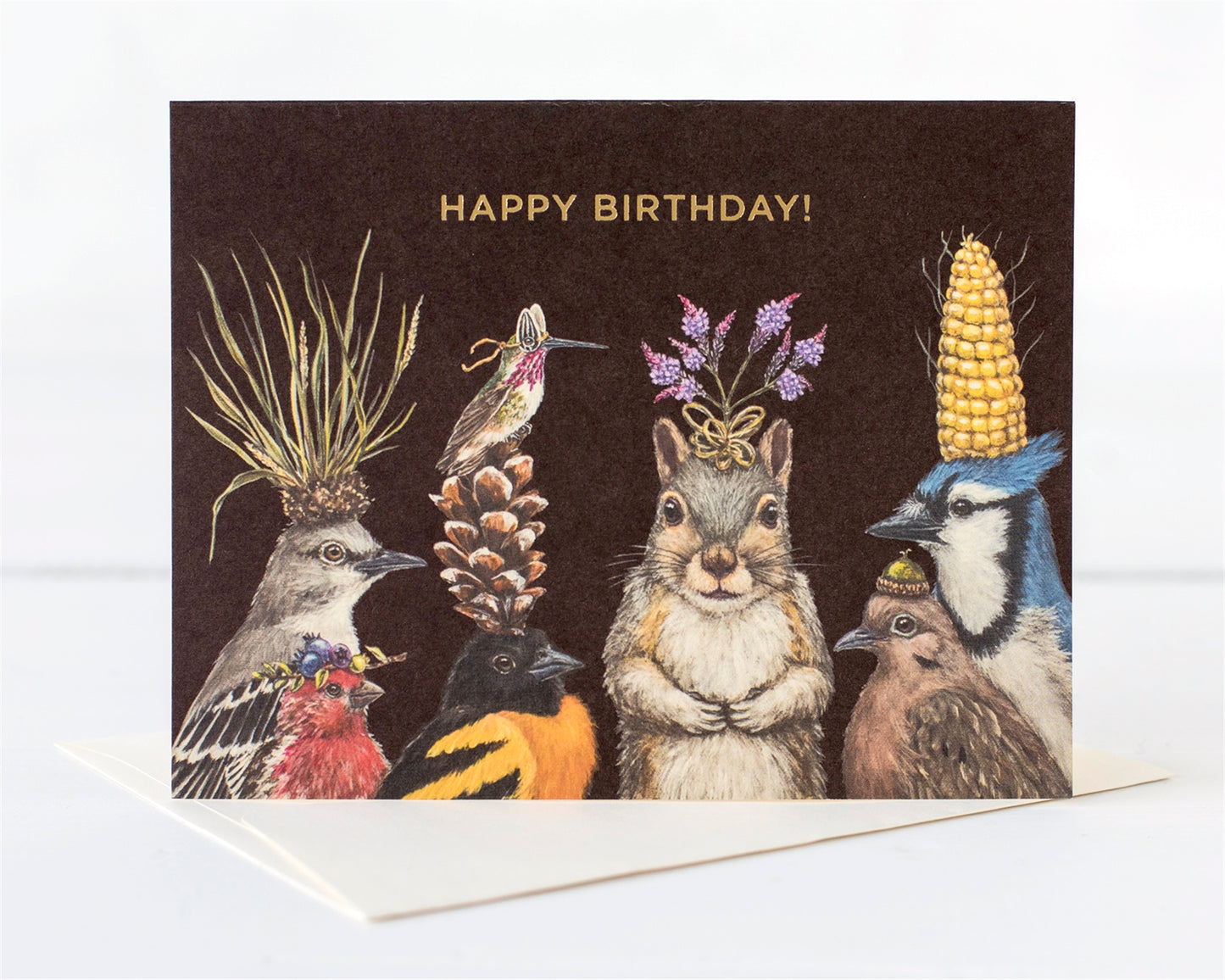A group of woodland creatures' heads adorned with nature's bounty of flowers, nuts, pinecones, dressed up to wish you Happy Birthday 
